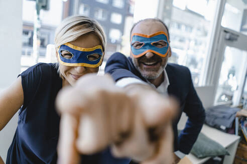 Businessman and woman, wearing super hero masks, pointing at camera - KNSF06339