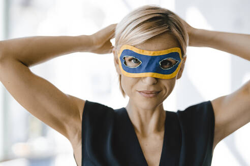 Portrait of blond businesswoman, wearing superwoman mask - KNSF06357