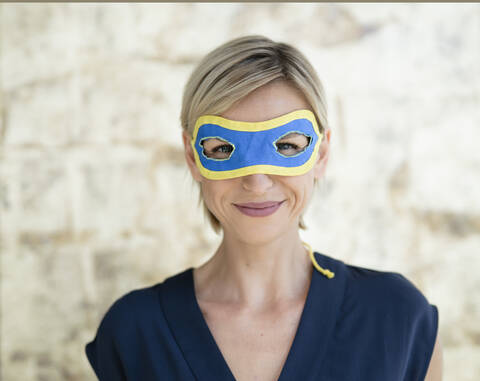 Porträt einer blonden Geschäftsfrau, die eine Superwoman-Maske trägt, lizenzfreies Stockfoto