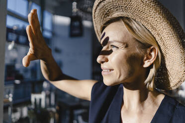 Woman wearing staw hat, shielding her face from the sun - KNSF06384