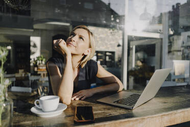 Blonde Frau mit Laptop in einem Café - KNSF06386