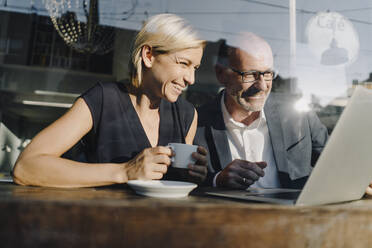 Geschäftsmann und Frau sitzen in einem Café und benutzen einen Laptop - KNSF06388