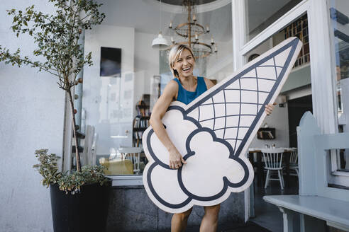 Woman standing in front of her coffee shop, holding icecream sign - KNSF06397