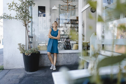 junge Geschäftsinhaberin, die vor ihrem Café steht, lizenzfreies Stockfoto