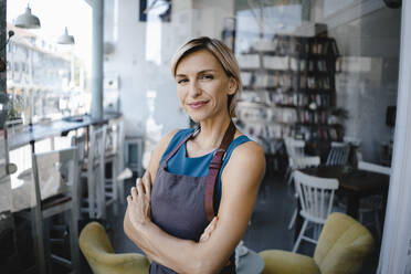 Portrait of blond woman, standing in front of her own coffee shop - KNSF06409