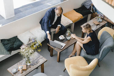 Businessman and woman having a meeting in a coffee shop, discussing work - KNSF06415