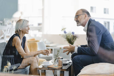 Businessman and woman having a meeting in a coffee shop, discussing work - KNSF06416