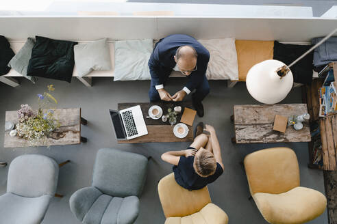 Businessman and woman having a meeting in a coffee shop, discussing work - KNSF06418