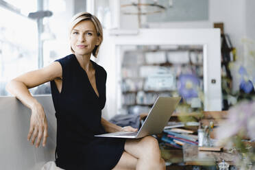 Businesswoman sitting in coffee shop, using laptop - KNSF06421