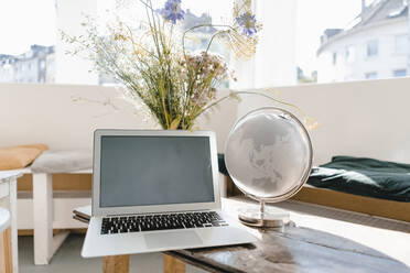 Laptop and globe on a table in a coffee shop - KNSF06431