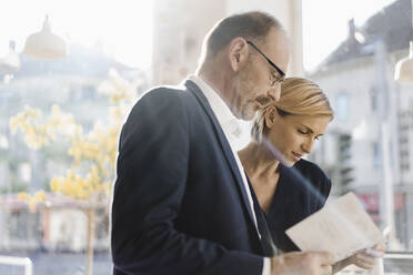 Businessman and woman reading menu in a coffee shop - KNSF06433