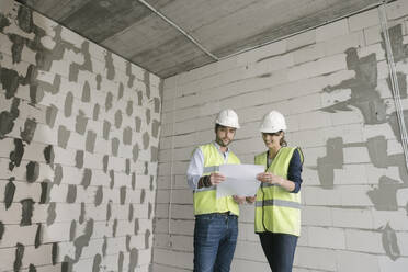 Two architects talking while standing at construction site - AHSF00804