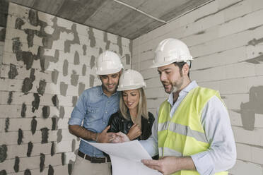 Architect talking about architectural plan with future owners on construction site - AHSF00816