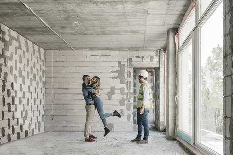 Architekt bei einem Treffen mit glücklichen zukünftigen Eigentümern auf der Baustelle, lizenzfreies Stockfoto