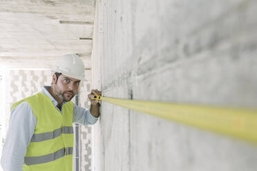 Architekt beim Vermessen einer Wand auf der Baustelle - AHSF00825