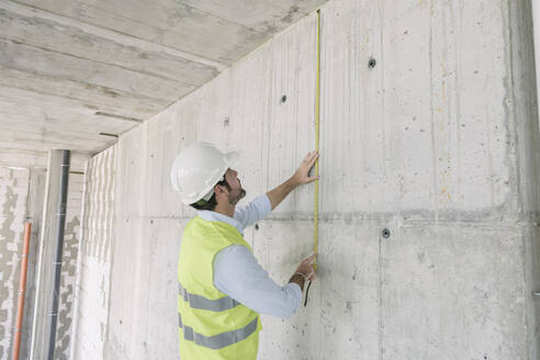Architekt beim Vermessen einer Wand auf der Baustelle - AHSF00828