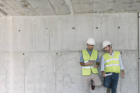 Zwei Arbeiter benutzen ein Tablet auf einer Baustelle - AHSF00833