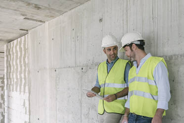 Zwei Arbeiter benutzen ein Tablet auf einer Baustelle - AHSF00834