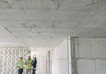 Male architects and female manager using tablet at construction site - AHSF00836