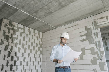 Architect checking architectural plan on construction site - AHSF00837