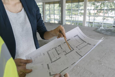 Male architect and female manager talking about architectural plan at construction site - AHSF00845