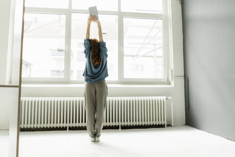 Rückenansicht einer Frau in einem Loft bei einer Dehnungsübung, lizenzfreies Stockfoto