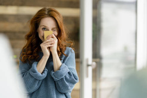 Portrait of redheaded woman with credit card in a loft - KNSF06473