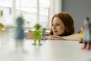 Porträt einer rothaarigen Geschäftsfrau in einem Loft mit Miniaturrobotern auf dem Schreibtisch - KNSF06479