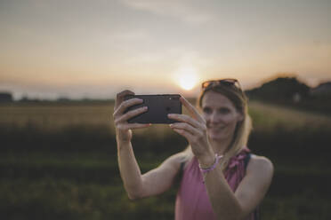 Frau macht ein Selfie bei Sonnenuntergang - CHPF00574