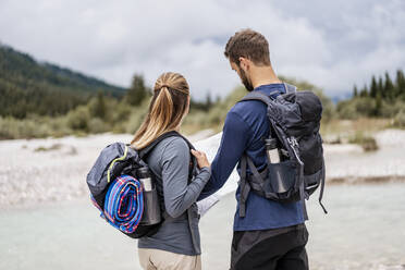 Young couple on a hiking trip reading map, Vorderriss, Bavaria, Germany - DIGF08253