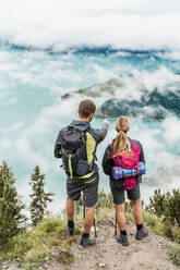 Young couple on a hiking trip in the mountains looking at view, Herzogstand, Bavaria, Germany - DIGF08271