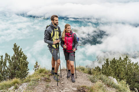 Selbstbewusstes junges Paar bei einer Wanderung in den Bergen, Herzogstand, Bayern, Deutschland, lizenzfreies Stockfoto