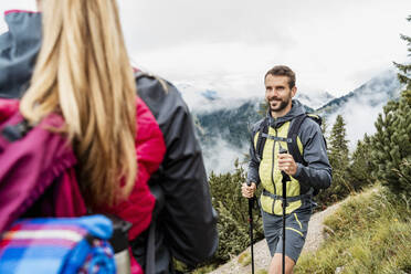 Smiling young couple on a hiking trip in the mountains, Herzogstand, Bavaria, Germany - DIGF08279