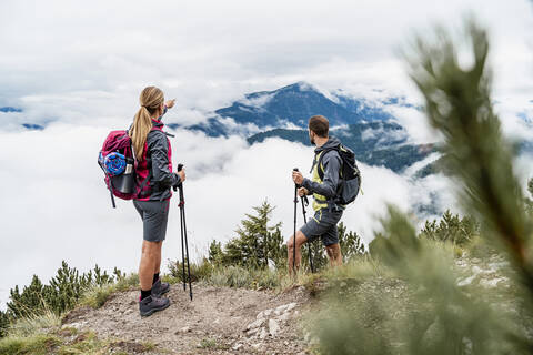 Junges Paar bei einer Wanderung in den Bergen mit Blick auf die Aussicht, Herzogstand, Bayern, Deutschland, lizenzfreies Stockfoto