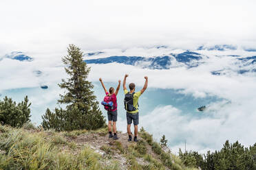 Glückliches junges Paar mit erhobenen Armen bei einer Wanderung in den Bergen, Herzogstand, Bayern, Deutschland - DIGF08286