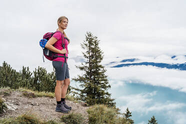 Junge Frau auf einer Wanderung in den Bergen mit Blick auf die Aussicht, Herzogstand, Bayern, Deutschland - DIGF08290