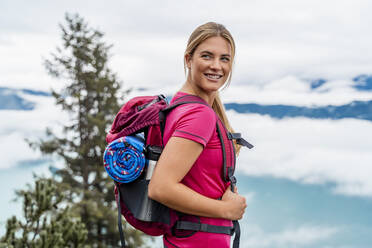Smiling young woman on a hiking trip in the mountains, Herzogstand, Bavaria, Germany - DIGF08292