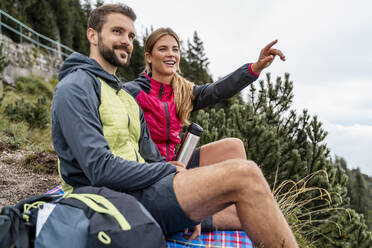 Happy young couple on a hiking trip in the mountains having a break, Herzogstand, Bavaria, Germany - DIGF08302