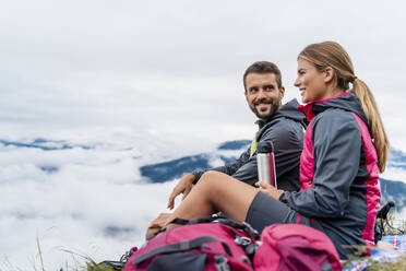 Junges Paar beim Wandern in den Bergen, das eine Pause macht, Herzogstand, Bayern, Deutschland - DIGF08305