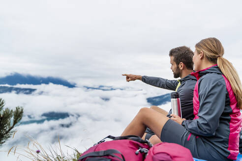 Junges Paar beim Wandern in den Bergen, das eine Pause macht, Herzogstand, Bayern, Deutschland - DIGF08306