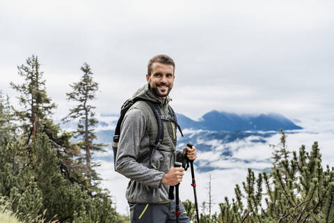 Lächelnder junger Mann bei einer Wanderung in den Bergen, Herzogstand, Bayern, Deutschland, lizenzfreies Stockfoto