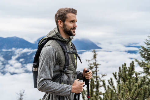 Confident young man on a hiking trip in the mountains, Herzogstand, Bavaria, Germany - DIGF08314