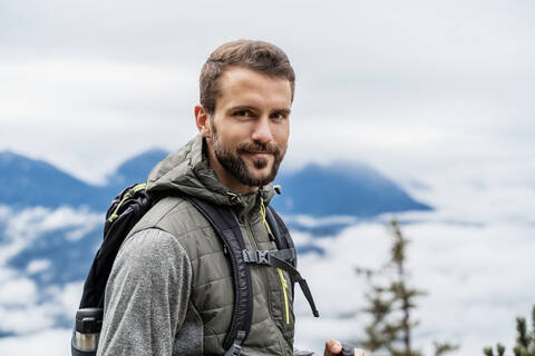 Porträt eines selbstbewussten jungen Mannes bei einer Wanderung in den Bergen, Herzogstand, Bayern, Deutschland, lizenzfreies Stockfoto