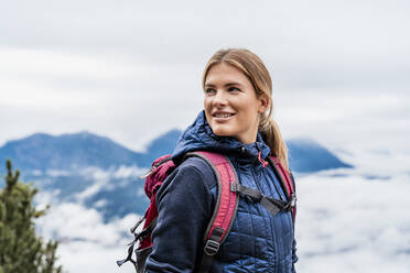 Smiling young woman on a hiking trip in the mountains, Herzogstand, Bavaria, Germany - DIGF08317