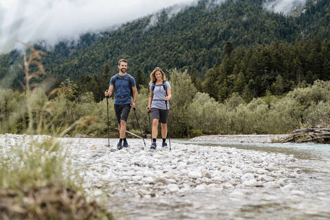 Junges Paar bei einer Wanderung am Flussufer, Vorderriss, Bayern, Deutschland, lizenzfreies Stockfoto