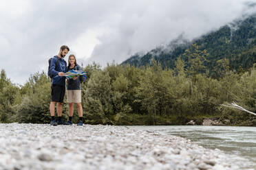 Junges Paar bei einer Wanderung am Flussufer beim Lesen einer Karte, Vorderriss, Bayern, Deutschland - DIGF08340