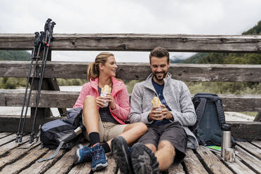 Junges Paar macht eine Pause auf einer Holzbrücke während einer Wanderung, Vorderriss, Bayern, Deutschland - DIGF08351