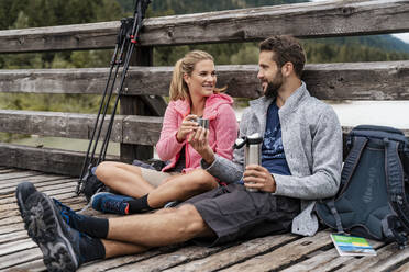 Young couple having a break on a wooden bridge during a hiking trip, Vorderriss, Bavaria, Germany - DIGF08355