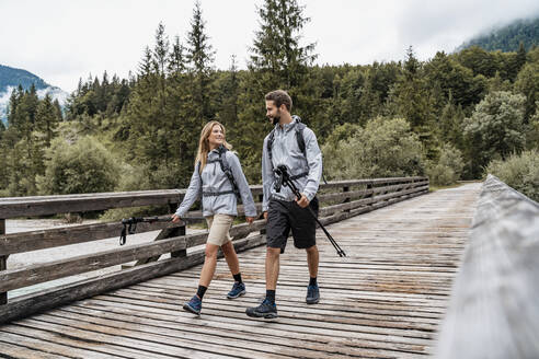 Junges Paar beim Wandern auf einer Holzbrücke, Vorderriss, Bayern, Deutschland - DIGF08369