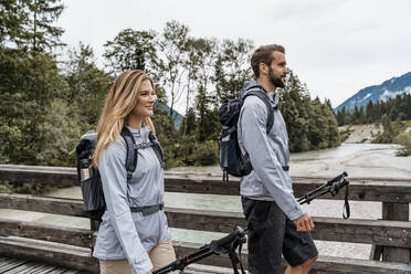 Confident young couple on a hiking trip walking on wooden bridge, Vorderriss, Bavaria, Germany - DIGF08371